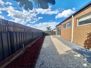 克莱基伯恩Home in Craigieburn的人行道旁的砖砌建筑,有栅栏