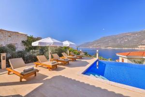 a pool with chairs and an umbrella next to the water at Villa Basil in Kaş