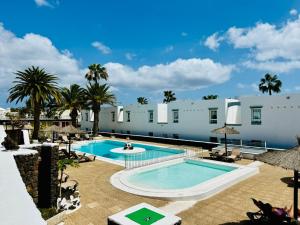 a resort pool with palm trees and white buildings at Little Gem in Matagorda