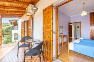 Un dormitorio con una cama y un balcón con mesa y sillas. en Dolce Far Niente, en Kato Korakiana