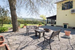 a patio with two chairs and a table and a tree at Casale Fattoria Benaris With Private Pool - Marsiliana in Marsiliana
