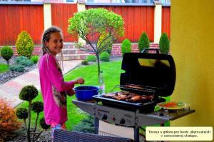 une jeune fille qui cuisine de la nourriture sur un grill dans l'établissement Chalupa Riviéra a Apartmány Riviéra - Liptov Bešeňová, à Ružomberok
