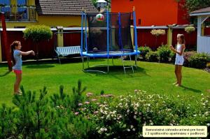 deux filles jouant avec un ballon sur un trampoline dans l'établissement Chalupa Riviéra a Apartmány Riviéra - Liptov Bešeňová, à Ružomberok