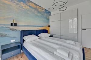 a bedroom with a blue bed with a painting on the wall at Comfort Apartments Botanika in Gdańsk