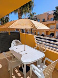 a white table and chairs on a balcony with an umbrella at Royal Cabanas Golf by Amandio Batista in Cabanas de Tavira