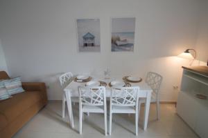 tavolo bianco da pranzo con sedie bianche e divano di Giada a Baia Verde