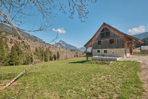 a barn in a field with mountains in the background at Les 3 Som in Saint-Pierre-de-Chartreuse