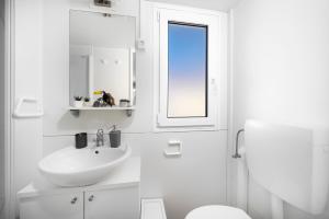 a white bathroom with a sink and a toilet at NIKO Mobile Home in Biograd na Moru +16 photos