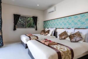 a hotel room with two beds and a window at Carmus-チャームーズ- in Nakijin +12 photos