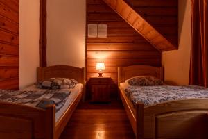 two beds in a room with wooden walls at Agroturystyka Pod Małą Górą in Łopuszna
