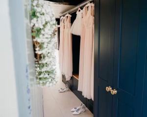 a walk in closet with pink dresses and shoes at Old Manor House, an idyllic country house in Shabbington