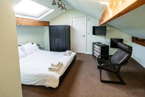 a bedroom with a bed and a chair and a television at The Lodge Harrogate in Harrogate