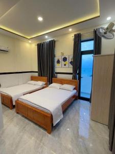 a bedroom with two beds and a large window at Nhà Nghỉ Phát Lợi in Quy Nhon
