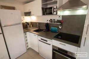 a kitchen with white cabinets and a white refrigerator at Villa T3 à 400m de la plage avec piscine in Vias +37 photos