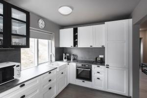 a kitchen with white cabinets and a clock on the wall at The Apartment at Reykjanesviti in Hafnir +30 photos