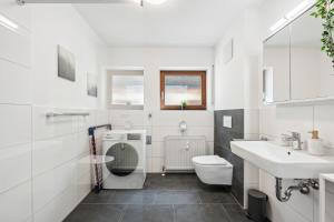 a white bathroom with a toilet and a sink at Sali Homes Weingenuss Eichbrunnen - Zentral in Obersulm