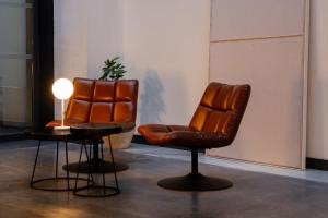 two leather chairs and a table with a lamp at Letoh Letoh Sevilla in Seville