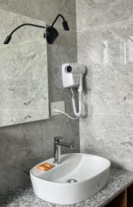 a bathroom with a sink and a light on the wall at Sterling Wood Hotel in Bengaluru
