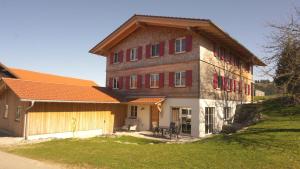 a large brick building with red shutters on it at Ferienwohnung Reitemann in Oy-Mittelberg
