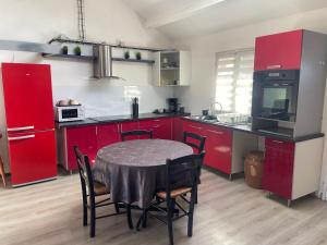a kitchen with red cabinets and a table with chairs at La maison du Bas in Naours