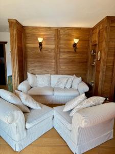 a living room with two white couches and wooden walls at Charme alpino e modernità-Appartamento ristrutturato a due passi dal centro in Cortina dʼAmpezzo