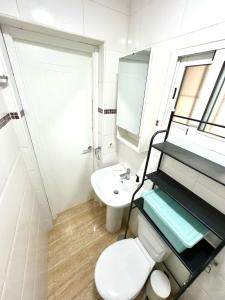 a white bathroom with a toilet and a sink at Rosaleda Centro Apartamento in Málaga +11 photos