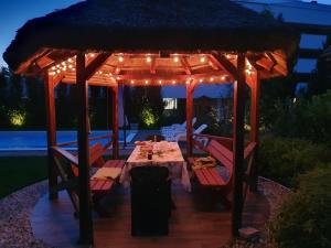 a dining table under a gazebo with lights at Szemes Villa in Balatonszemes