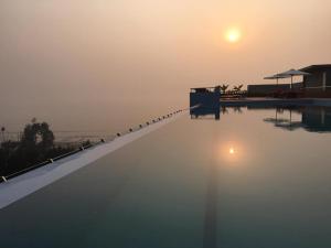 ein Schwimmbecken, über dem die Sonne untergeht in der Unterkunft Neeshorgo Hotel & Resort in Cox's Bazar
