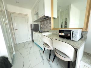 a kitchen with a counter with two chairs and a microwave at Новые апартаменты Empire Tower in Jomtien Beach