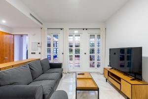 salon z kanapą i telewizorem z płaskim ekranem w obiekcie Triana Betis w Sewilli