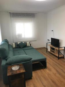 a living room with a green couch and a television at O Fogar do Moucho - Tres Marias Apartments in Redondela
