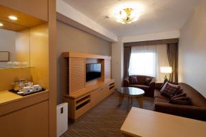 a living room with a couch and a television in a hotel room at Ueda Tokyu REI Hotel in Ueda