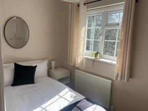une chambre avec un lit, un miroir et une fenêtre dans l'établissement 2 Bedroom Townhouse near Cardiff Bay and City Centre with Garden and Parking, à Cardiff