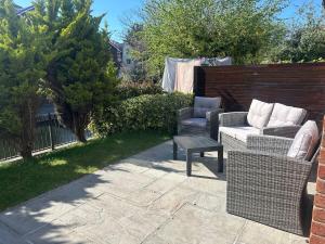 une terrasse avec deux chaises, un canapé et une table dans l'établissement 2 Bedroom Townhouse near Cardiff Bay and City Centre with Garden and Parking, à Cardiff