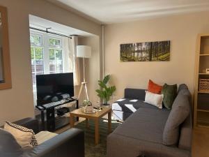 un salon avec un canapé et une télévision dans l'établissement 2 Bedroom Townhouse near Cardiff Bay and City Centre with Garden and Parking, à Cardiff