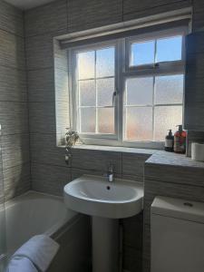 une salle de bains avec lavabo, fenêtre et baignoire dans l'établissement 2 Bedroom Townhouse near Cardiff Bay and City Centre with Garden and Parking, à Cardiff 21 autres photos