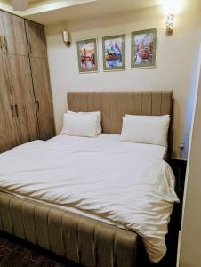 ラーワルピンディーにあるLuxury Apartmentsの部屋にある白いシーツと枕が置かれたベッド
