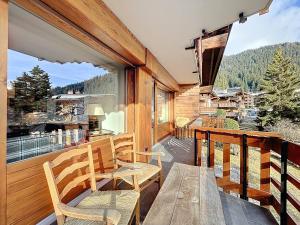 a balcony with two chairs and a wooden table at Trois Mélèzes 105 in Verbier