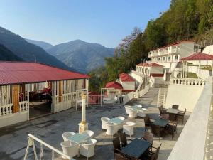 a building with tables and chairs on a patio with mountains at kotbari hotel in Yārsa