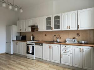 Una cocina con gabinetes blancos y un refrigerador blanco. en Apartament Mickiewicza, en Olsztyn
