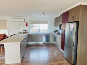 eine Küche mit Küchengeräten aus Edelstahl und Holzschränken in der Unterkunft Jestalong House - Pet Friendly Outside - 4 De Guichen Dr in Robe