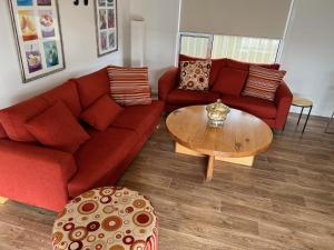 ein Wohnzimmer mit einem roten Sofa und einem Tisch in der Unterkunft Jestalong House - Pet Friendly Outside - 4 De Guichen Dr in Robe + 20 Fotos