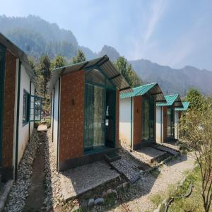 una fila de casas con montañas en el fondo en The Raajas - Camp & Resorts, en Rishīkesh