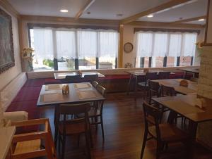 a dining room with tables and chairs and windows at City Street Hotel in Gjirokastër