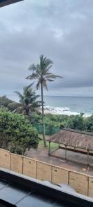 a view of a beach with a bench and palm trees at Unwind and Relax in Amanzimtoti