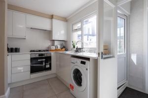 カーディフにあるSanjo Suite - Sleek 2BR Home with Parking & WIFIの白いキッチン(洗濯機、シンク付)
