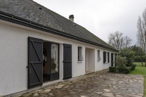 a white house with black doors and a stone driveway at Villa de la Salmonière - Maison avec piscine et jardin clos in La Roche-Blanche