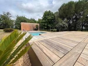 a backyard with a wooden deck and a swimming pool at Villa de la Salmonière - Maison avec piscine et jardin clos in La Roche-Blanche
