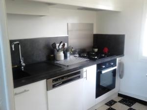 a kitchen with white cabinets and a black counter top at Maison vue Panoramique in Vailhan