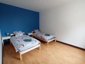 two beds in a room with blue walls and wooden floors at Gîte la Blanchère in Saint-Herblon